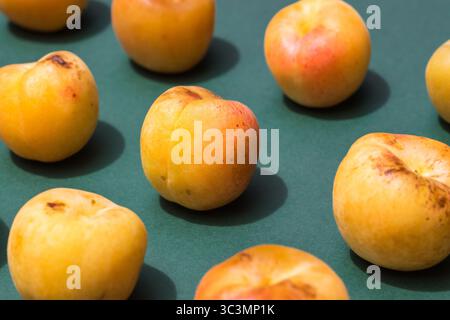 From above, a collection of fresh apricots is arranged on a dark green paper background, highlighting their vibrant orange hues and smooth textures, c Stock Photo