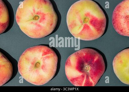 Top view of six ripe, juicy peaches arranged in a grid on a dark, textured surface. The vibrant red and yellow fruits contrast beautifully against the Stock Photo