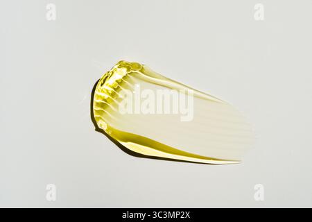 Close-up of a yellow gel smear on a  light beige background, showcasing its textured surface and smooth, glossy appearance. The image highlights simpl Stock Photo
