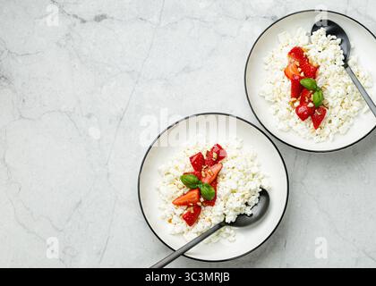 Two elegant white plates filled with creamy cottage cheese topped with fresh strawberry slices, creating a delicious and visually appealing breakfast Stock Photo