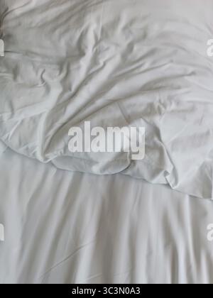 Empty wrinkled white bedding, close up, hotel, white pillows Stock Photo