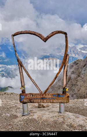 Wooden heart shaped photo frame at the Serauta stop on the Marmolada cable car with cloud shrouded mountains in the background. Stock Photo