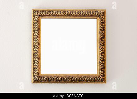 Ornate golden empty picture frame on the wall, square front view blank mockup Stock Photo