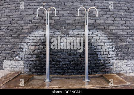 Outdoor fresh water shower on the beach against a stone wall. Modern minimalist design, exterior elements. High quality photo Stock Photo