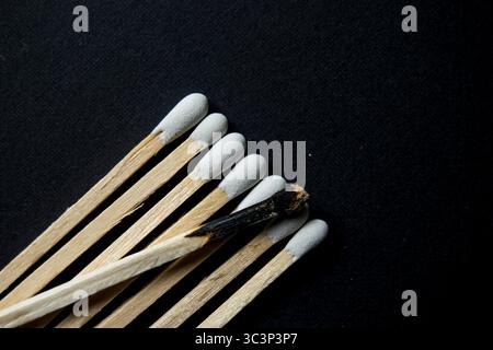 Long matches with a white tip, 1 spent match laying across the top all on a black background Stock Photo