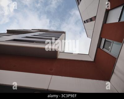 A low-angle view of modern buildings, with one structure featuring red walls and rectangular windows, and another with white and gray panels. The arch Stock Photo