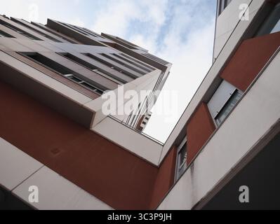 Tall, modern architectural structures viewed from below against a sky backdrop. The buildings feature geometric designs with a mix of white and red pa Stock Photo