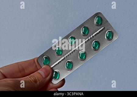 Hand holding a blister pack of green pills Stock Photo