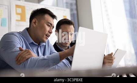 Multiracial focused teammates using digital tablet and laptop Stock Photo
