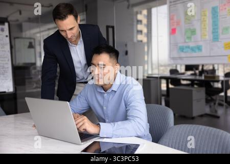 Two multiethnic employees using laptop in modern workplace Stock Photo