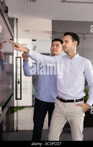 Colleagues analyzing data displaying on large monitor screen Stock Photo