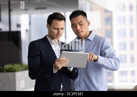 Two diverse professional men working together in office using tablet Stock Photo