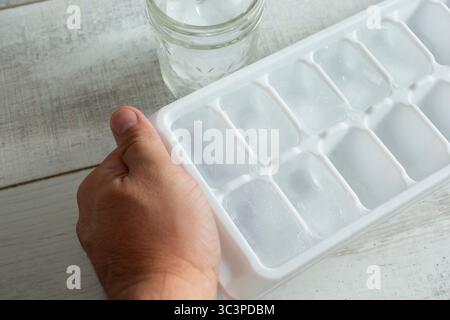 A view of a hand prepping an ice cube tray. Stock Photo