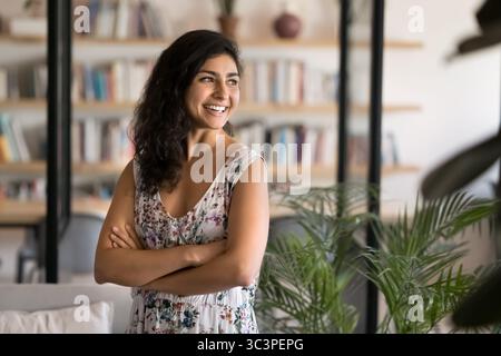 Businesswoman standing in professional workspace looks aside with smile Stock Photo