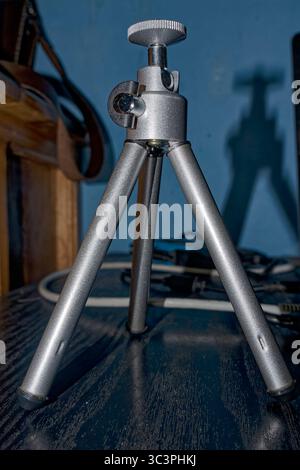 Miniature tripod for lights and very light cameras on computer table, USB and electrical cords behind in a small  office in a Nicaraguan house Stock Photo