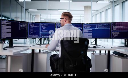 Male Software Engineer Typing Code On Office Computer Screen, Caucasian Programmer Stock Photo