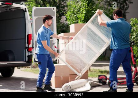 House Relocation: Movers Unloading Furniture From Truck For Delivery Stock Photo