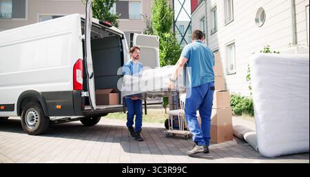 Hispanic Movers In Blue Uniform Loading Truck For Furniture Delivery Stock Photo
