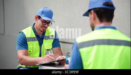 Skilled Electrician Working On Commercial HVAC System With Technician Team Stock Photo