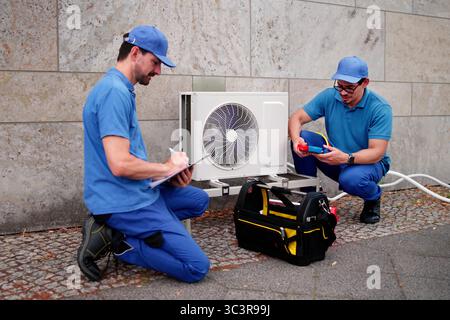 Experienced Hispanic HVAC Technician Installing Commercial Air Conditioning System. Stock Photo