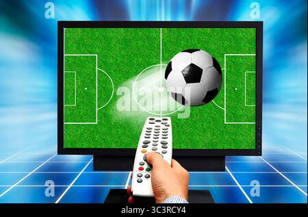 Watching soccer in 3D, remote control in hand as the ball appears to leap out of the TV screen Stock Photo