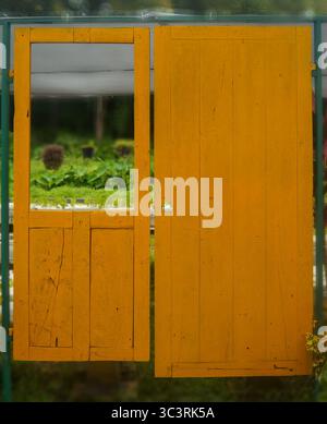 The surface of the homemade wooden door is painted bright yellow. Stock Photo