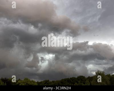 Dark discoloured thunderclouds Cloud roll moves over forest area above grey clouds Rain clouds herald thunderstorms, Germany Stock Photo