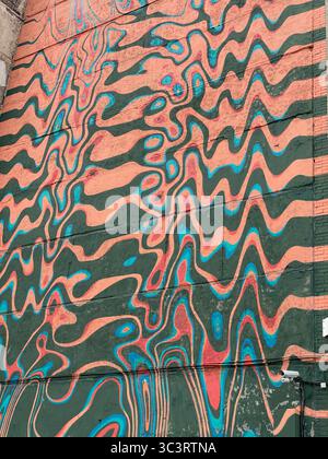 Psychedelic mural with wavy lines in vibrant teal, pink, and orange creating an abstract pattern. Mobile photo Stock Photo