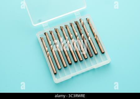 A set of metal milling cutters neatly arranged in a transparent plastic case on a blue background. Ideal for use with milling machines in various mach Stock Photo