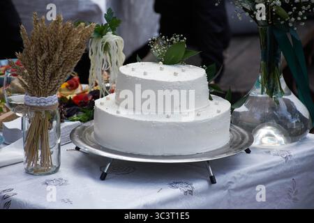 The hall was drowned in flowers: lush arches of roses and peonies, elegant bouquets with eucalyptus on the tables and a scattering of petals along the Stock Photo