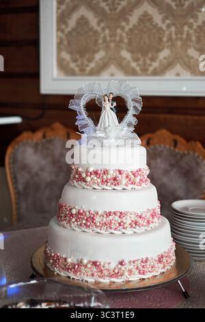 The hall was drowned in flowers: lush arches of roses and peonies, elegant bouquets with eucalyptus on the tables and a scattering of petals along the Stock Photo