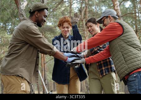 Diverse Young Adults Stacking Hands While Collaborating Outdoors in Forest Stock Photo