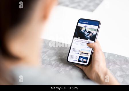 News in phone. Press release. Reading digital media. Mockup online newspaper in cellphone screen. Woman using mobile website. Latest article headlines. Stock Photo