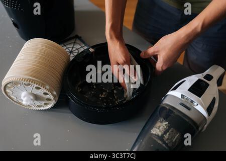 Top view of technician male cleaning inside of air humidifier using cloth, with vacuum cleaner nearby to remove dust and debris, ensuring proper Stock Photo