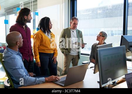 Diverse business team in a meeting collaborating on project in modern office using technology. Stock Photo