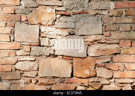 Old stone wall with rough, weathered surface and irregular stones, showing age and natural texture in close-up detail. Stock Photo