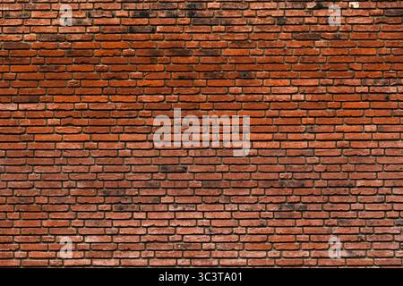 Weathered red brick wall with irregular texture and natural color variation Stock Photo