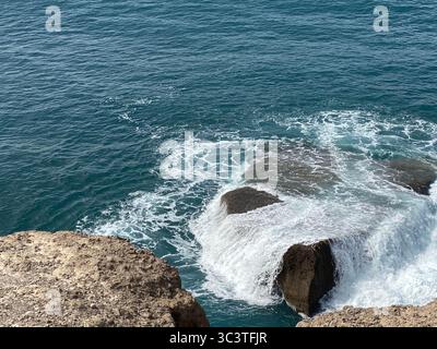Waves crashing against the rocky shore under a clear, blue sky in Canary Islands Stock Photo