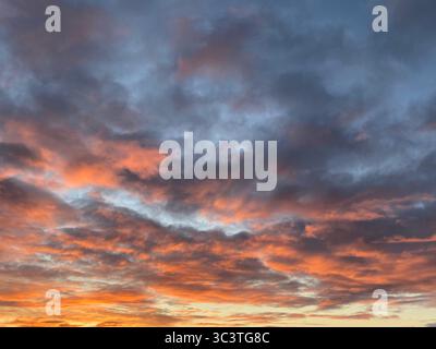 The sky ignites with brilliant colors as the sun dips below the horizon, a beautiful sunset. Stock Photo