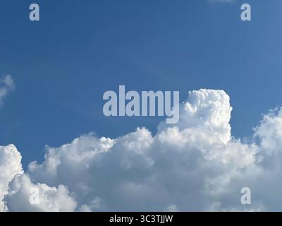 A stunning view of a puffy white cloud floating in a vibrant, clear blue sky. Stock Photo
