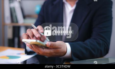 Cybersecurity concept with businessman holding smartphone and password login key icon. Online protection, data encryption, and mobile security. Stock Photo