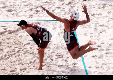 28 July 2024, Paris, France - Paris Olympics: Men’s Beach Volleyball.  Daniel Dearing of Canada serving to Ondrej Perusic and David Schweiner of the Czech Republic, as his teammate Samuel Schacter stands ready today at Eiffel Tower Stadium during the 2024 Paris Olympics.  Perusic and Schweiner won the match 2-0. Stock Photo
