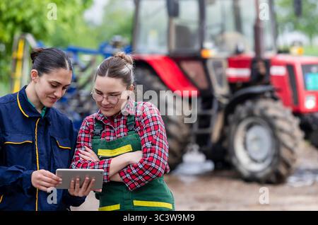 Two female farm workers looking at digital tablet, examining data on crops Stock Photo