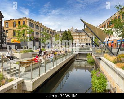 Cardiff, Wales, UK - 16 July 2025: Scenic landscape view of people resting on seats in the Canal Quarter in Cardiff city centre. Stock Photo