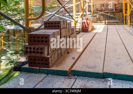 Old bricks neatly stacked on steel scaffolding with wood floor prior to being reinstalled on an existing building. Stock Photo