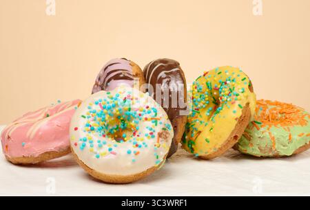 Stack of donuts with different toppings and glazes, beige background Stock Photo
