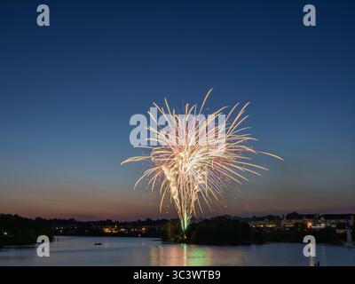 A magnificent, multi-colored fireworks show unfolds over Lake Ashburn in Ashburn Village, Virginia, lighting up the twilight. Stock Photo