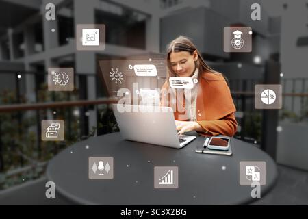 Young woman working on laptop outdoors with digital icons representing various concepts in a modern setting Stock Photo