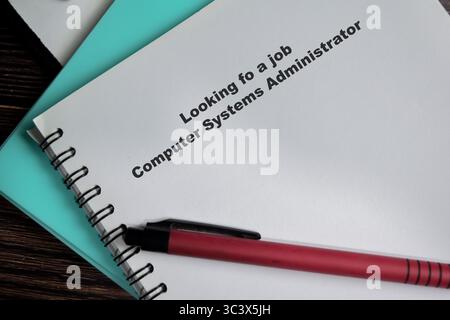 Concept of looking for a job computer systems administrator write on book isolated on Wooden Table. Stock Photo