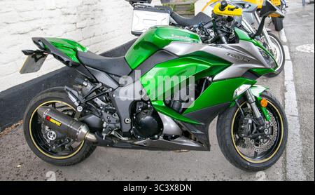 Green and black Kawasaki Ninja Z1000SX motorcycle parked on a street near a white brick wall at the Calne bike meet Stock Photo